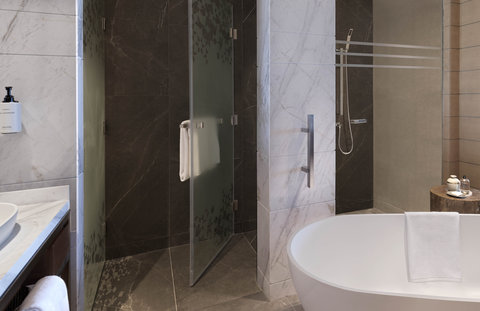 The bathroom offers ample space with a bathtub and walk-in shower